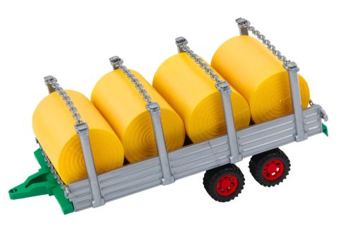 Nagy mezőgazdasági traktor pótkocsival és szénabálákkal, piros meghajtóval